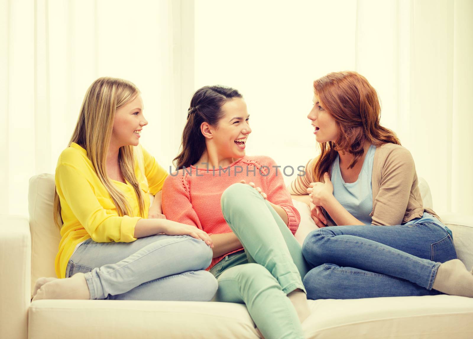 friendship and happiness concept - three girlfriends having a talk at home