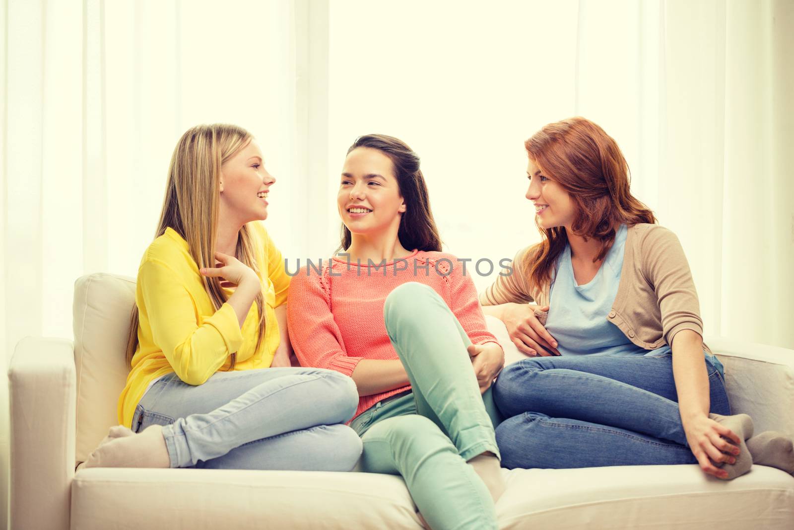 friendship and happiness concept - three girlfriends having a talk at home