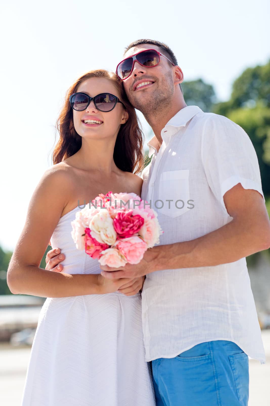 love, wedding, summer, dating and people concept - smiling couple wearing sunglasses with bunch of flowers hugging in city