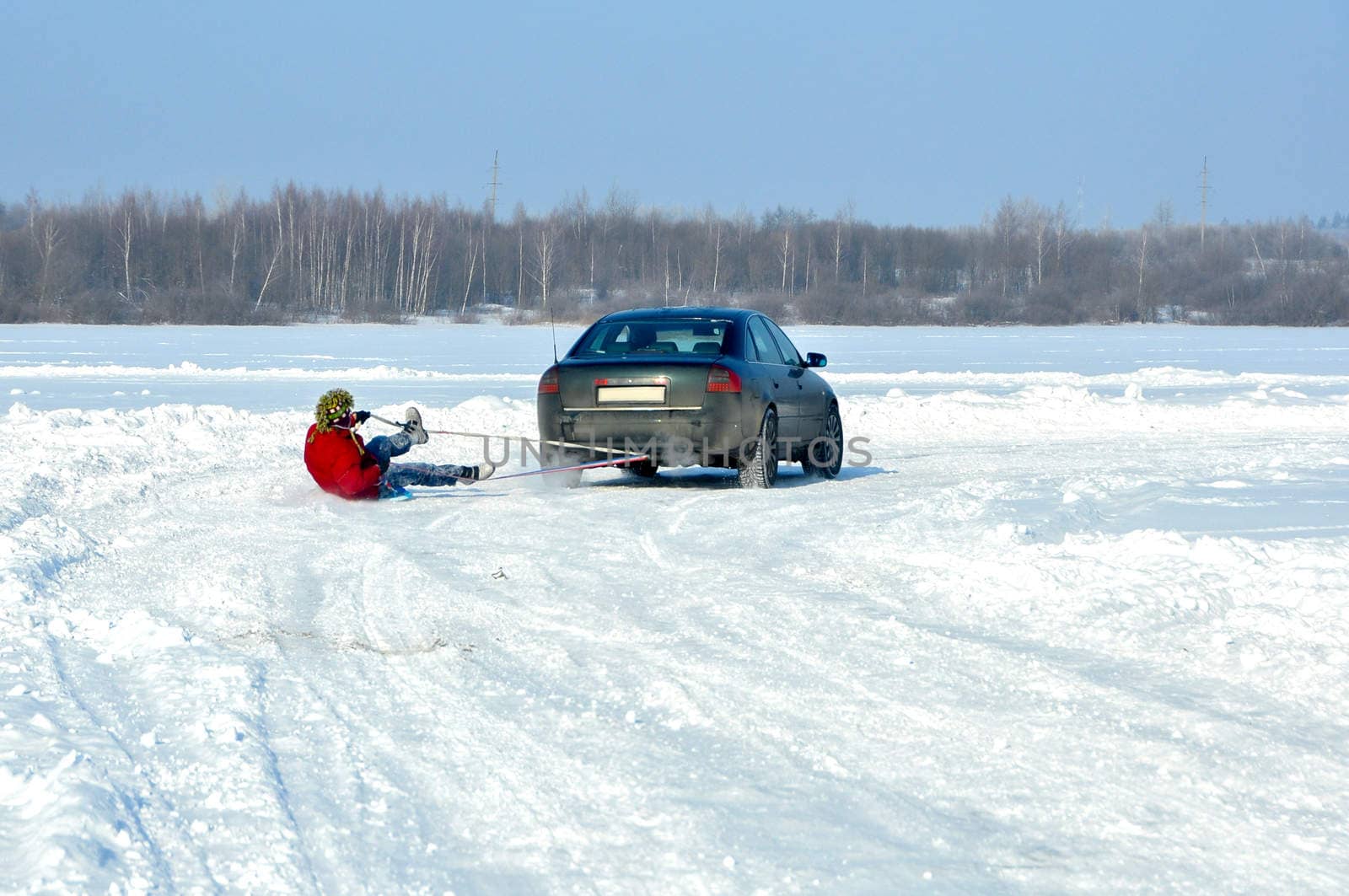 the car carrying the man on ice-boat  in tow in the snow