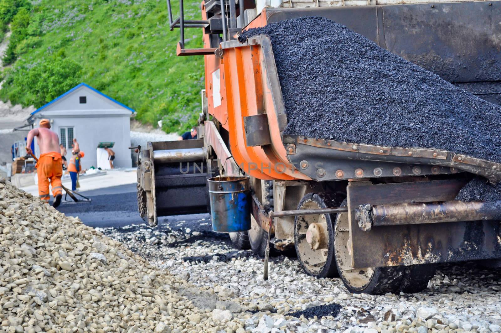 laying asphalt. asphalt paver machine and worker. by vlaru