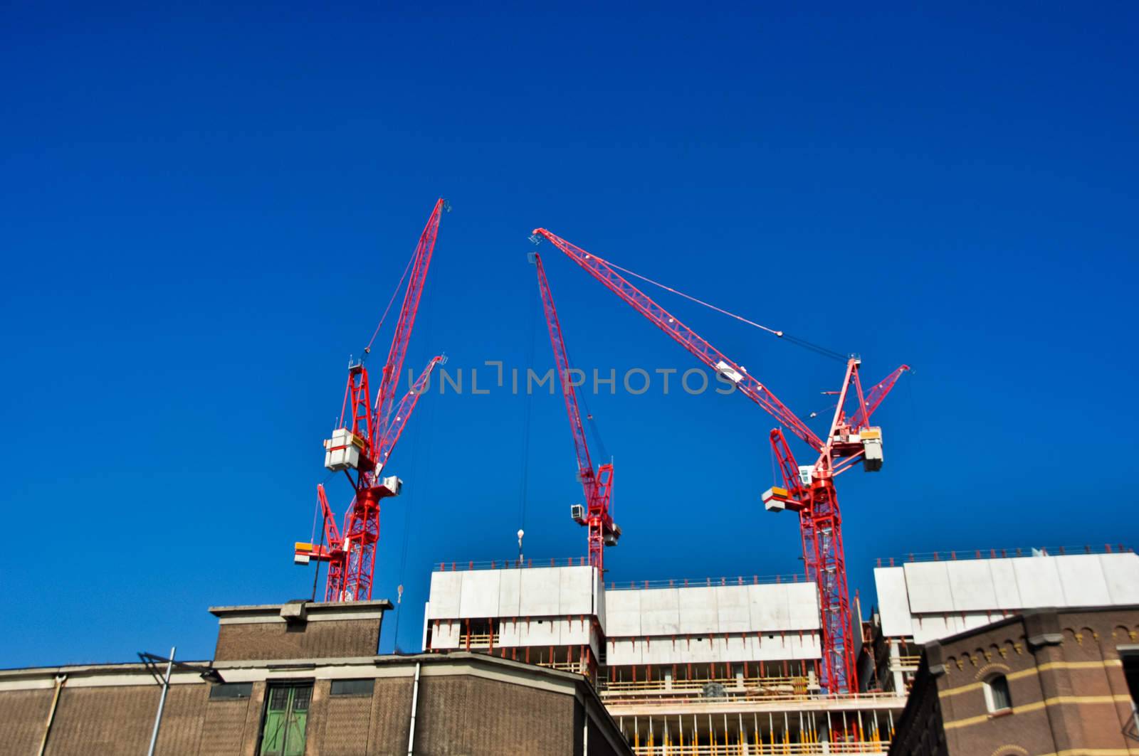 red construction  cranes on blue sky background by vlaru