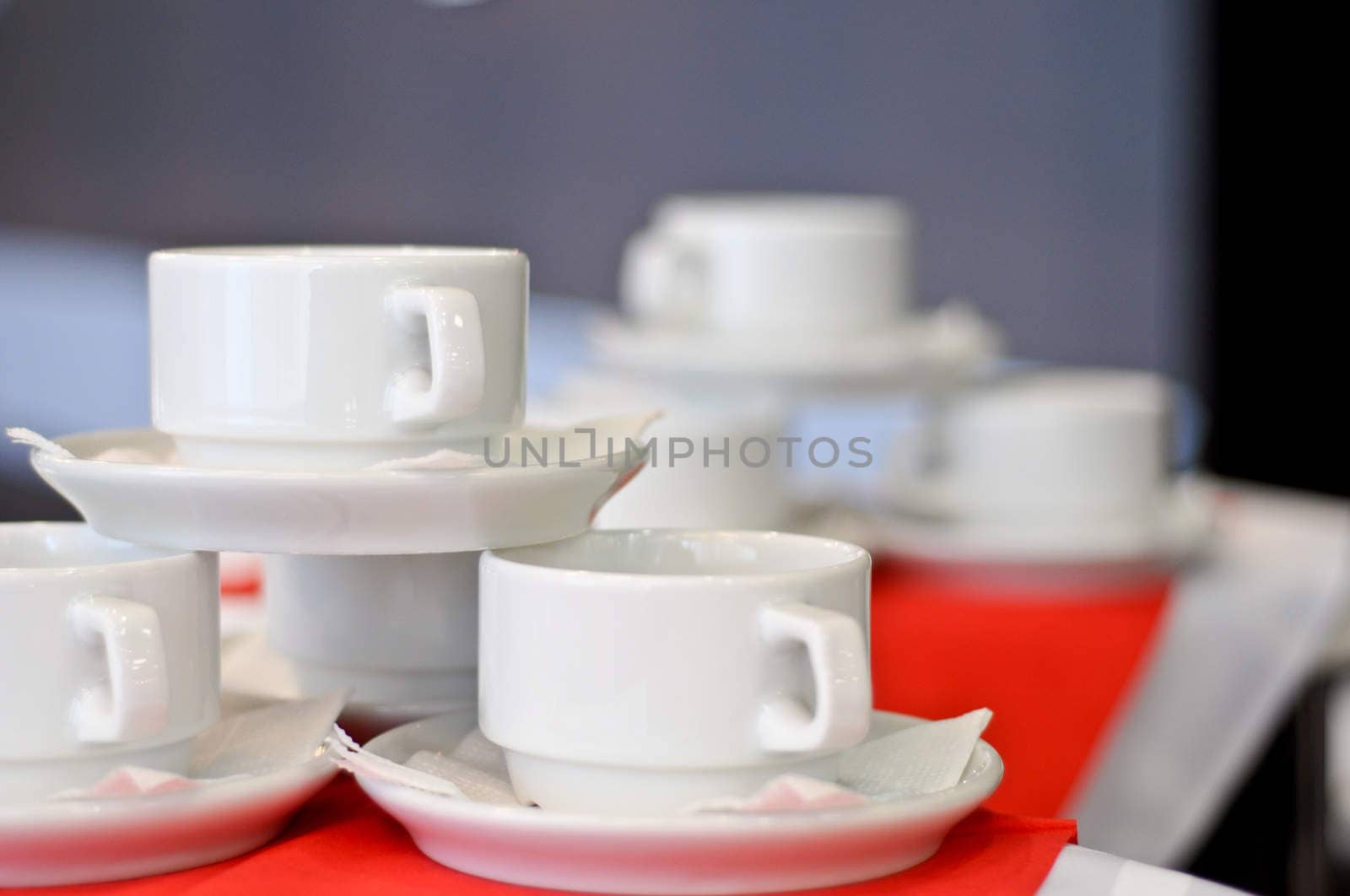 three white porcelain tea cups and saucers and napkins close up by vlaru