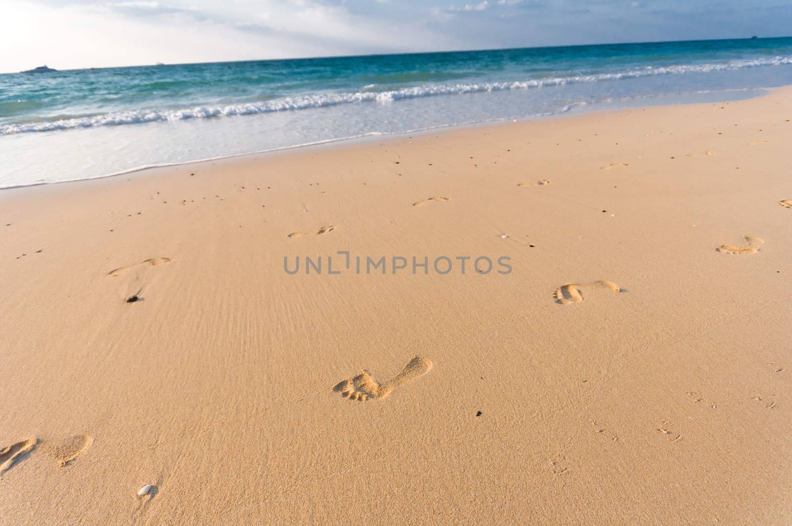 sandy beach with lots of footprints and a blue sky with clouds