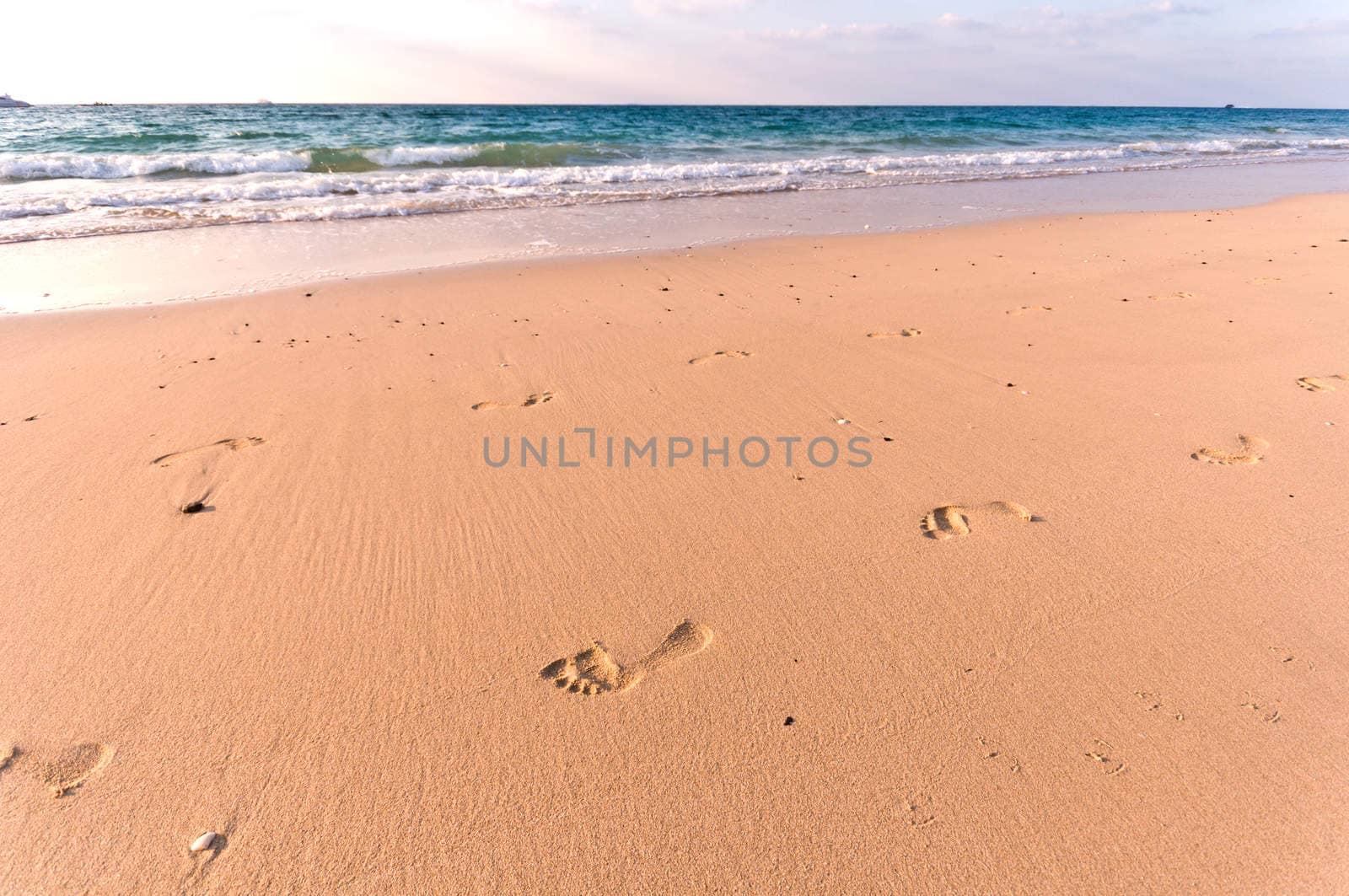 sandy beach with lots of footprints and a blue sky with clouds by vlaru