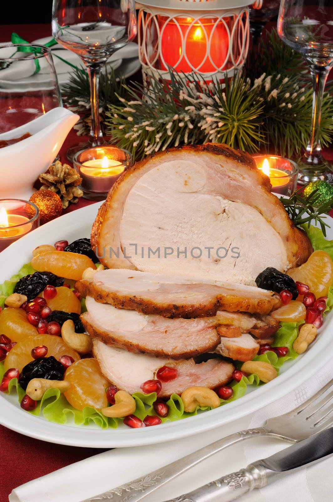 sliced baked turkey ham with fruit garnish on the Christmas table