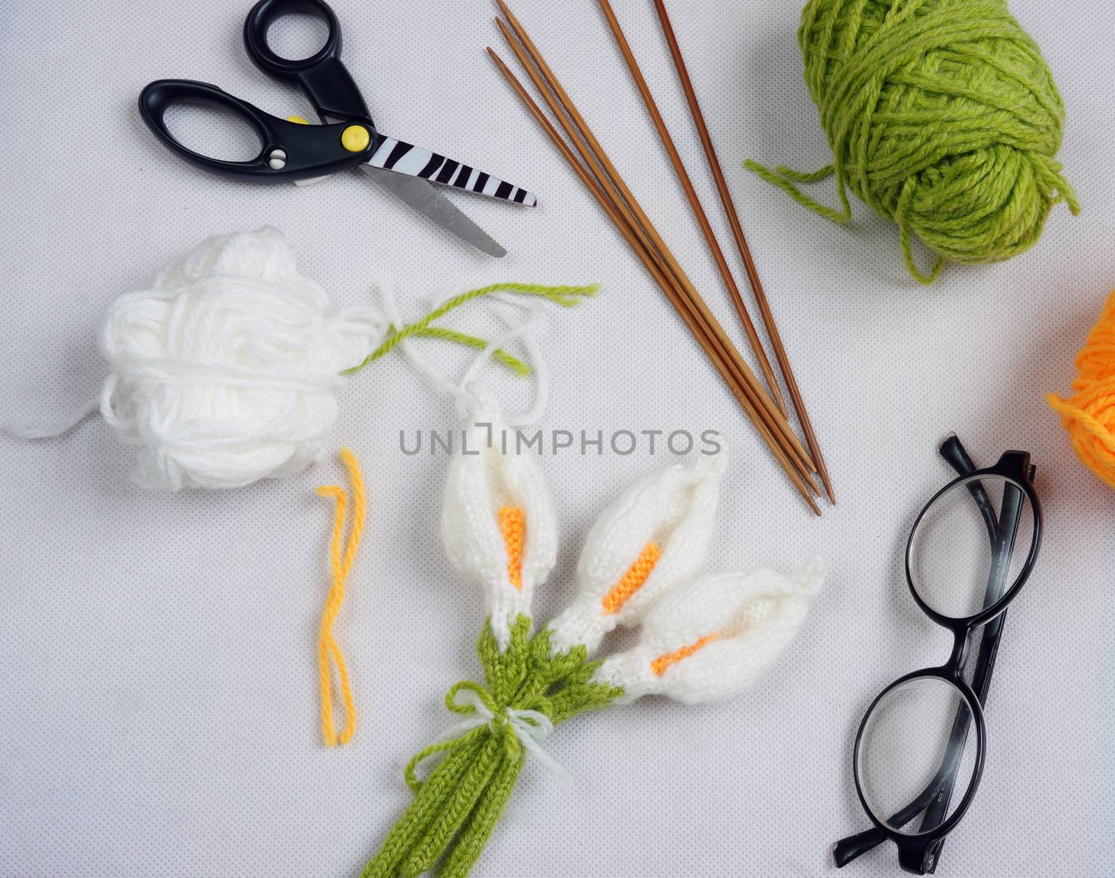 Romantic desk with ornament from handmade product, lily flower knit from white yarn, handbook, knitting pencil, coffee cup, glasses, beautifil craft