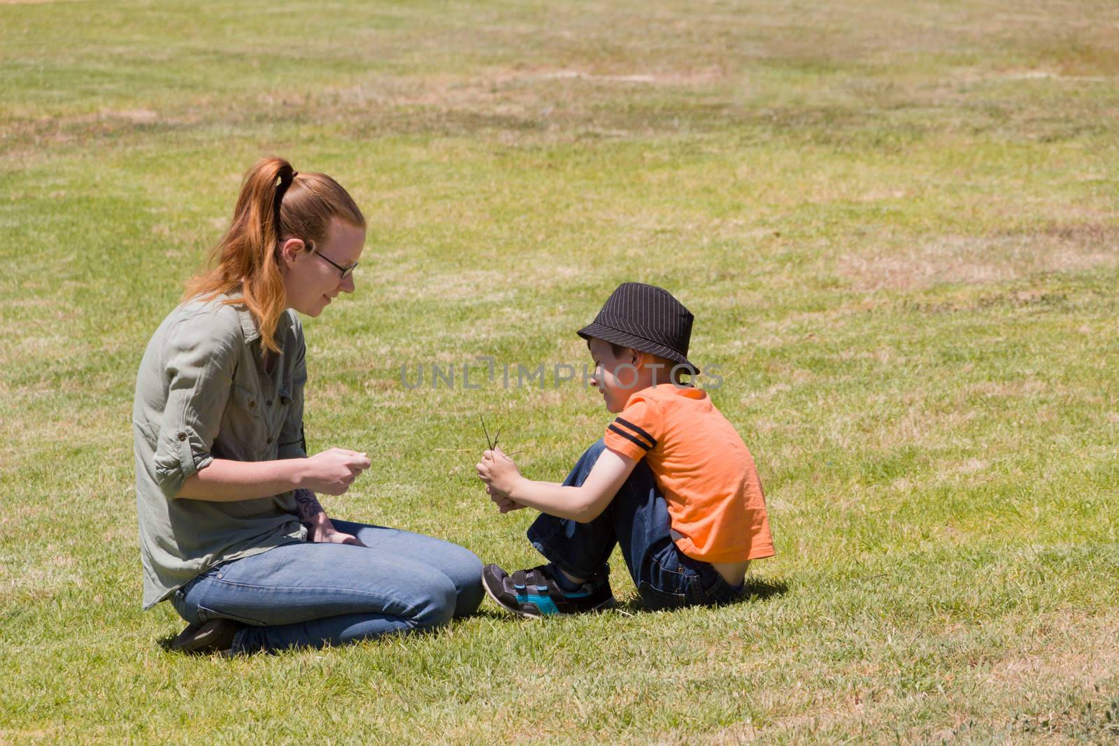 Happy scene of a mother and her son playing in a park on a suny day.