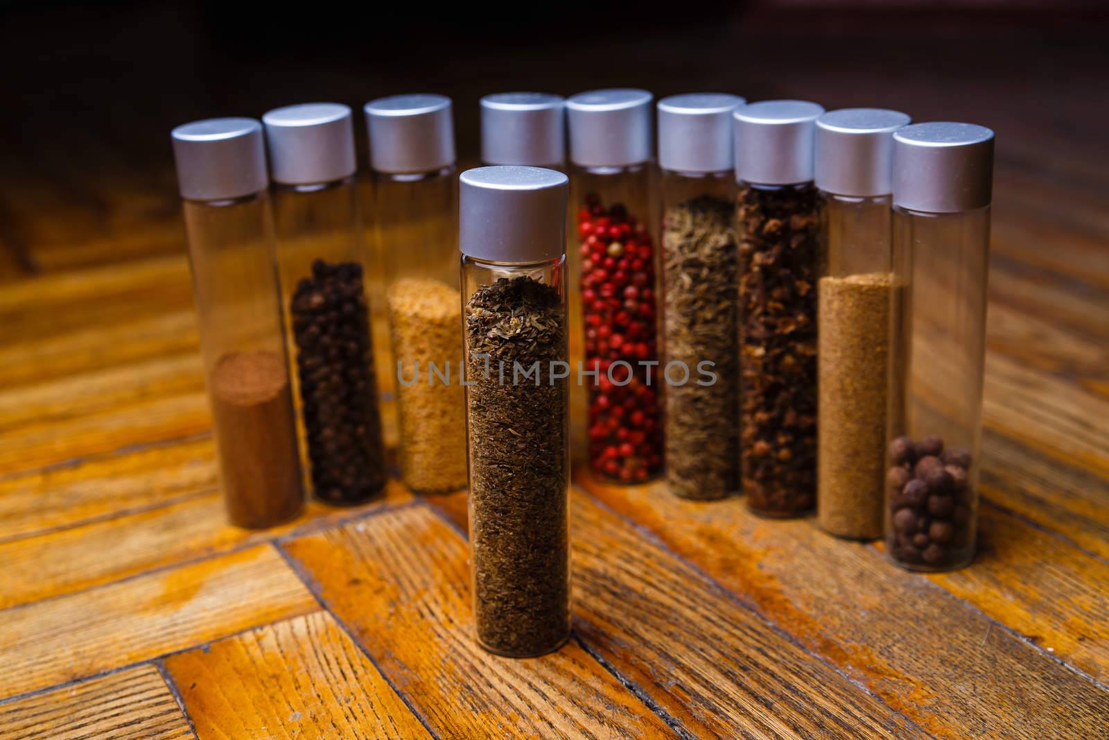 Assorted ground spices in bottles on wooden background