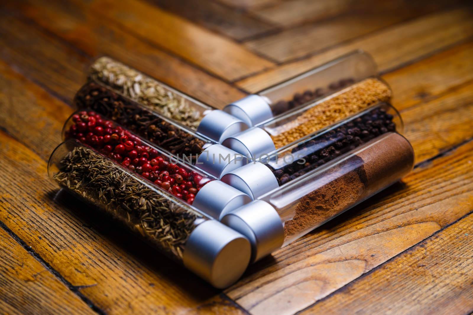 Assorted ground spices in bottles on wooden background