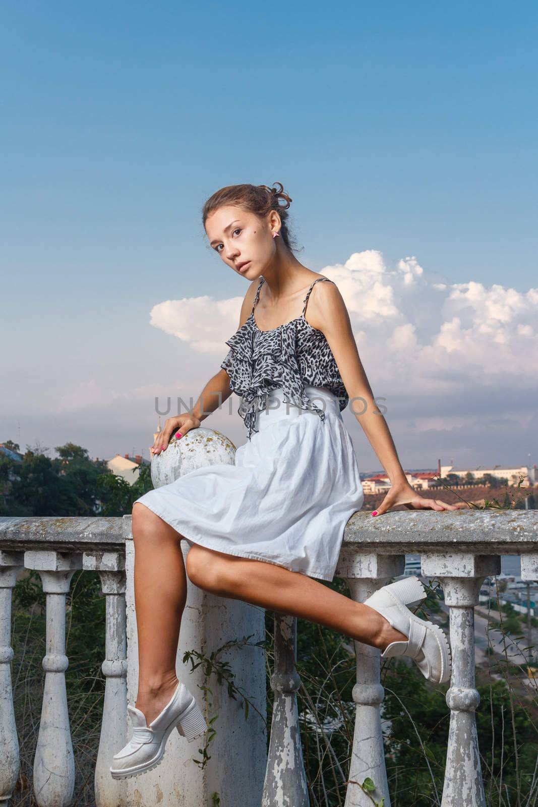 Beautiful young teen girl in bodysuit posing during city fashion shoot with classical building at background