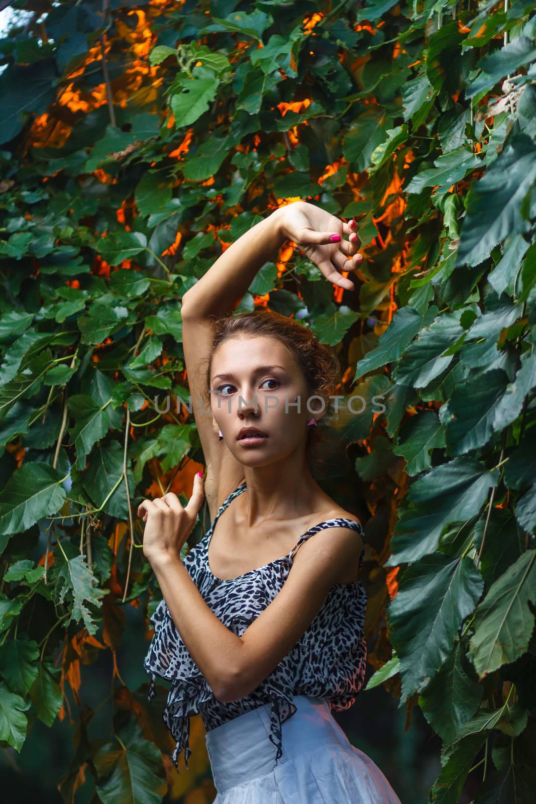 Fashion portrait shoot of a beautiful teen girl during city fashion photoshoot with greenery at background