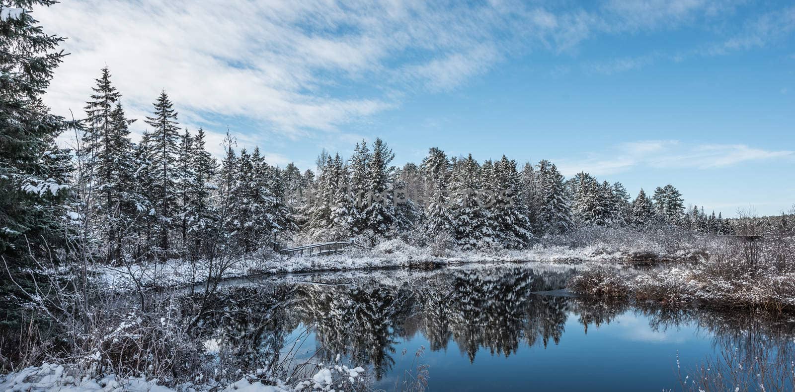 Chalk River foot bridge and nature trail walking path on a blue sky morning and fresh fallen snow.