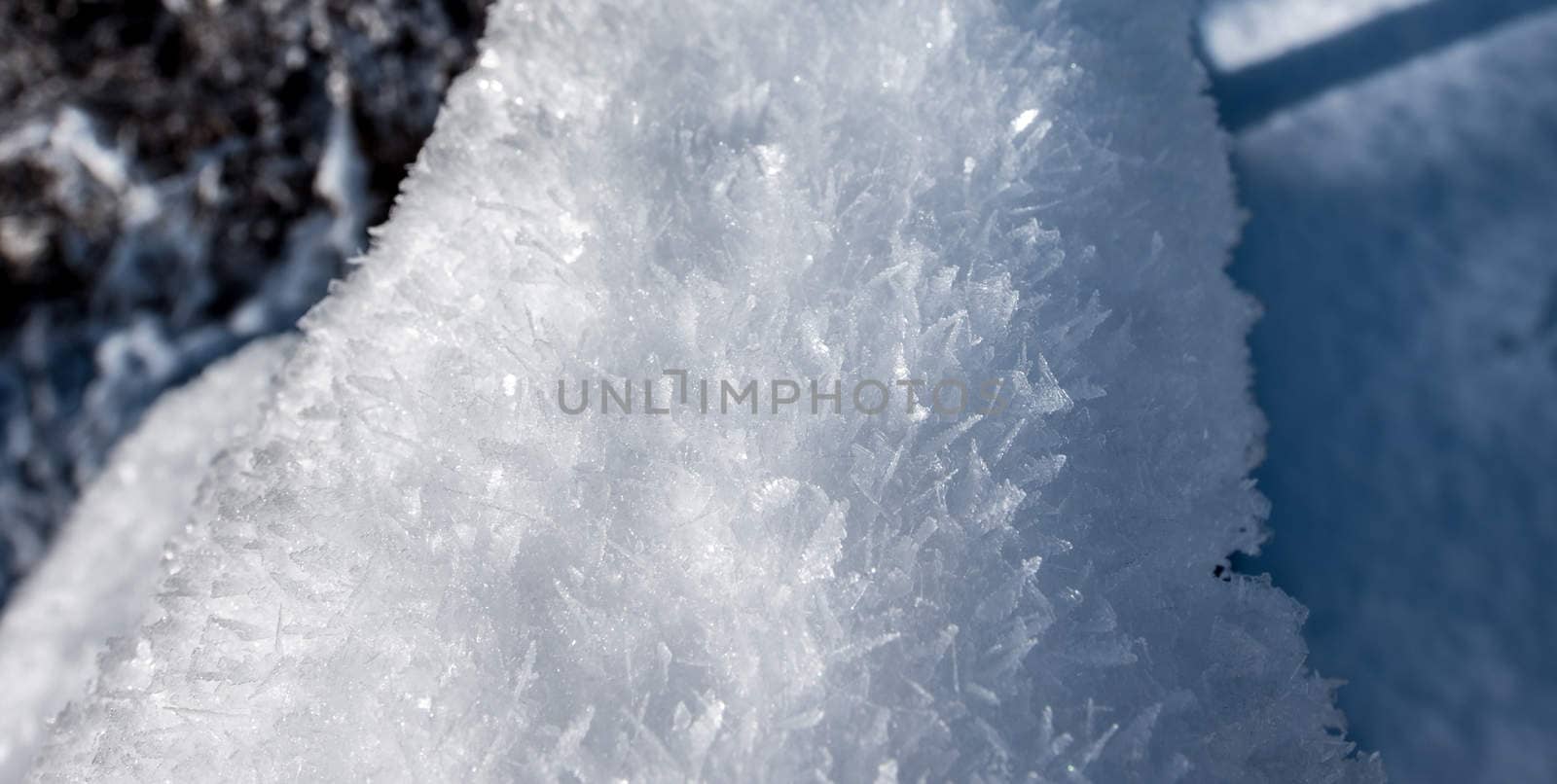 Snow flakes covered in large frost crystals. Fresh fallen snow, further covered by layers of frost, manifesting from the warmer water's rising mist nearby.