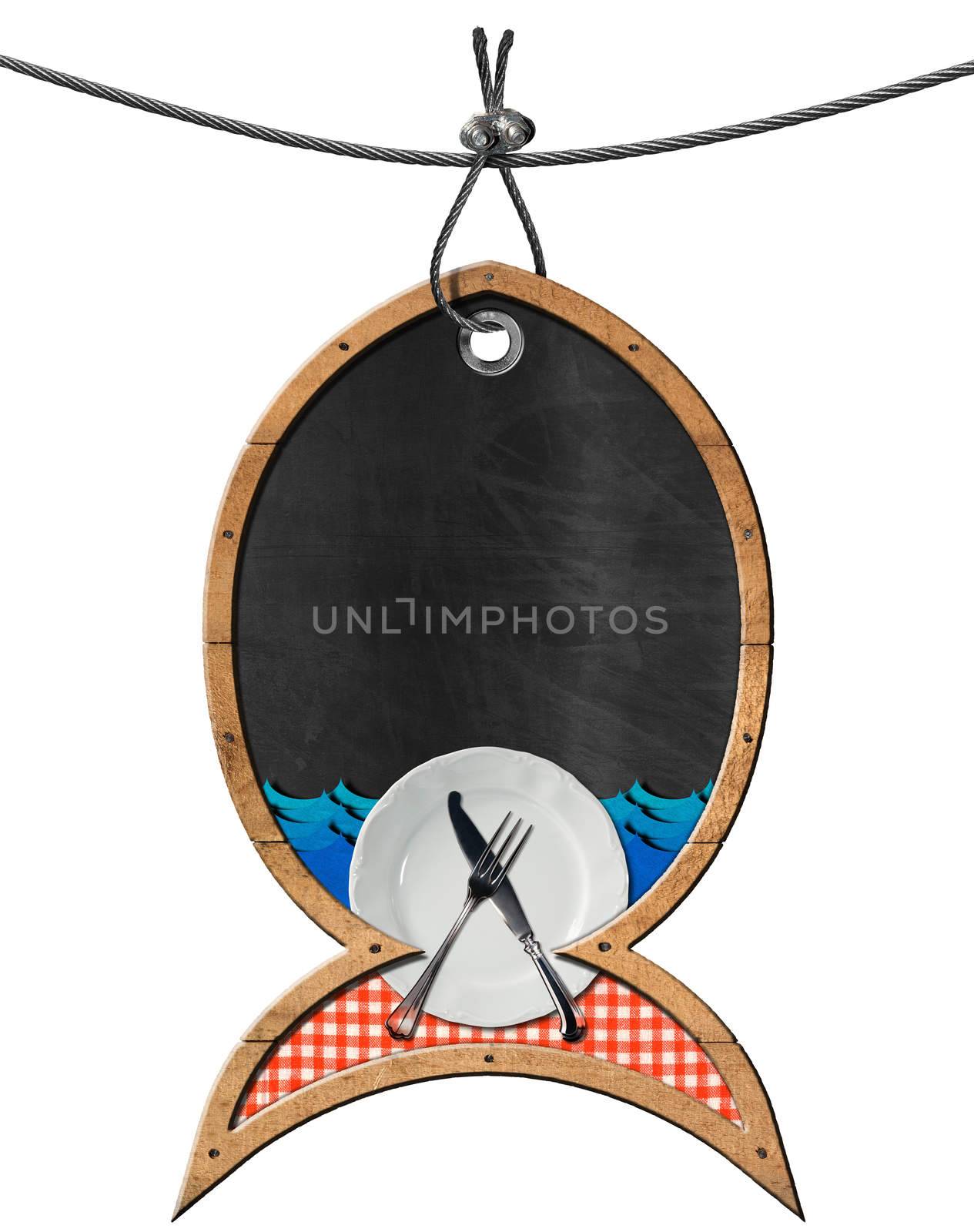 Empty blackboard in the shape of fish with plate, cutlery, checkered tablecloth and blue waves. Isolated on white and hanging from a steel cable