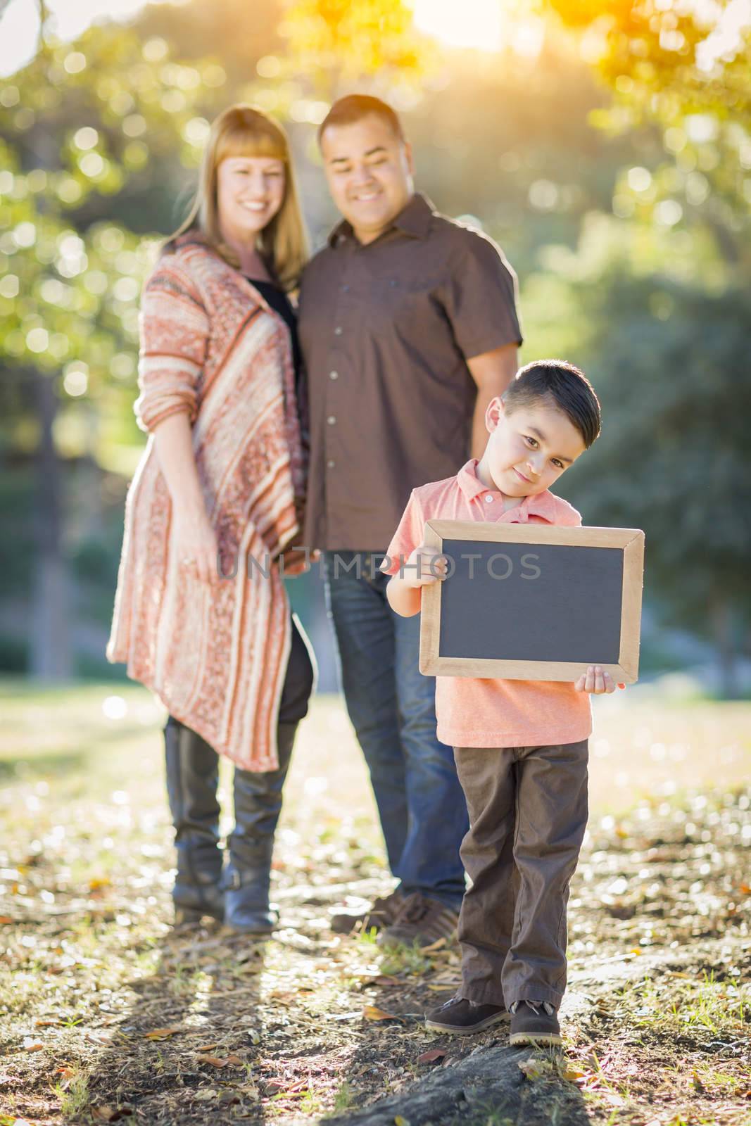 Mixed Race Couple Stands Behind Son with Blank Chalk Board by Feverpitched