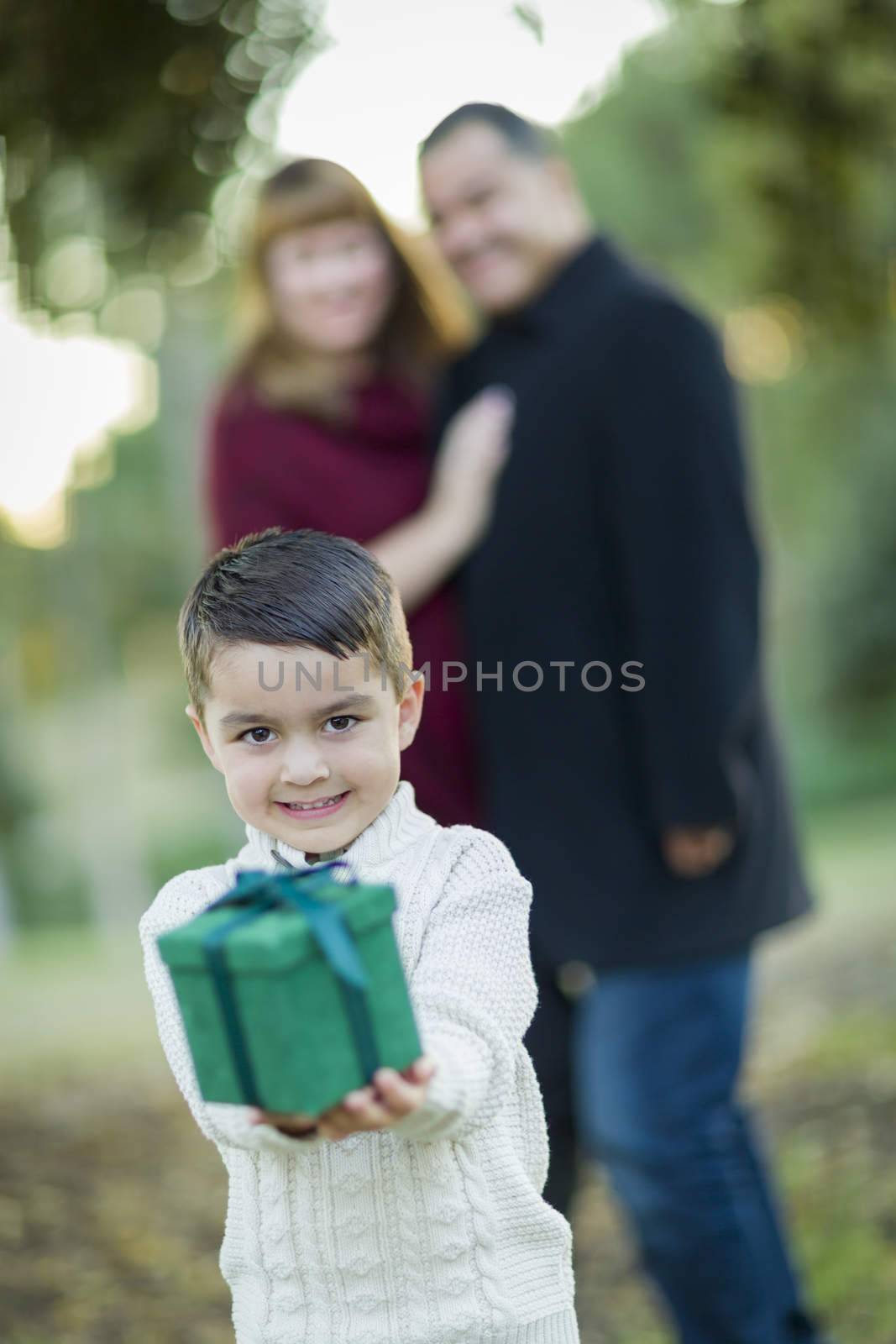Young Mixed Race Boy Holding Gift In Front with Parents Behind.