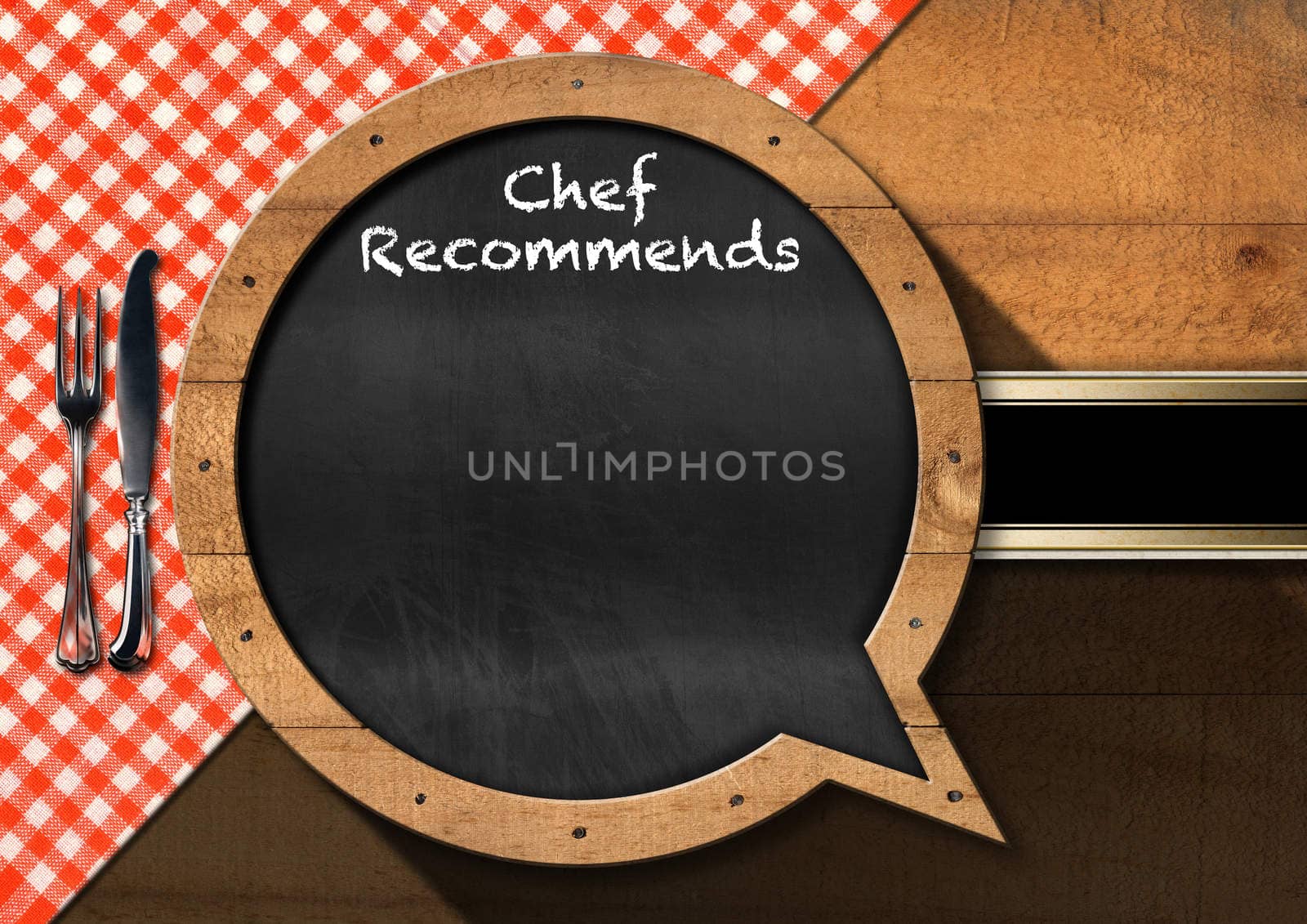 Blackboard in the shape of speech bubble with text Chef Recommends and silver cutlery on a wooden table with a checkered tablecloth