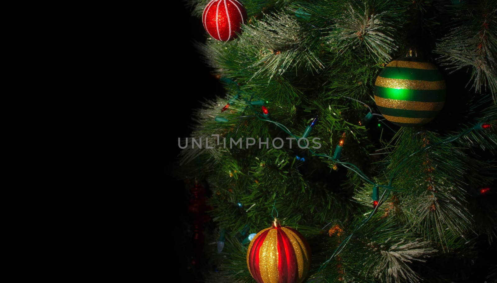 christmas tree branchs with balls and lights on black background