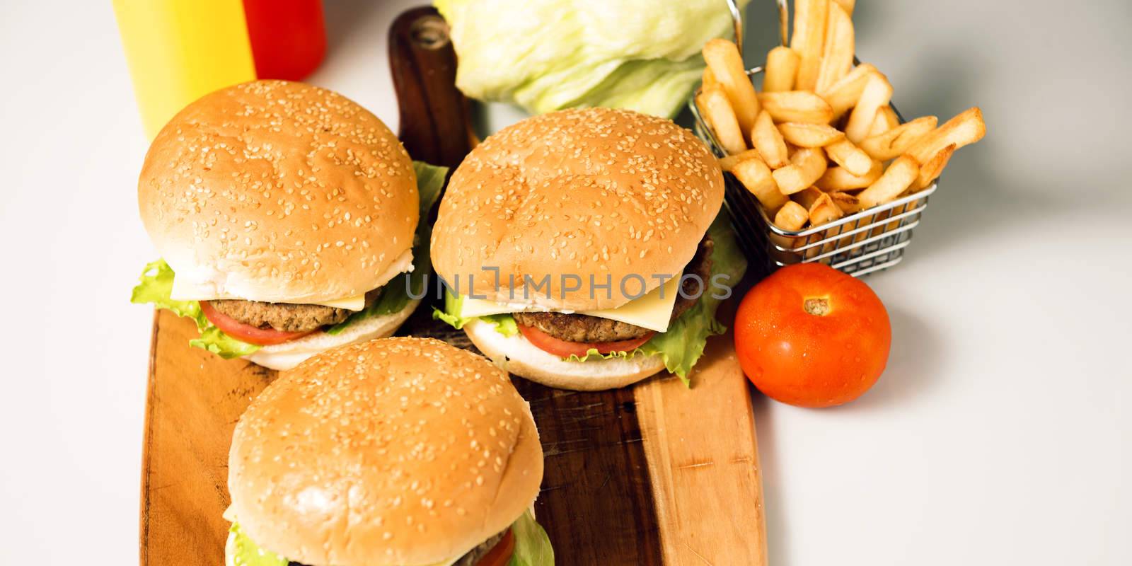 Hamburgers with cheese, potato chips and ingredients on a white background