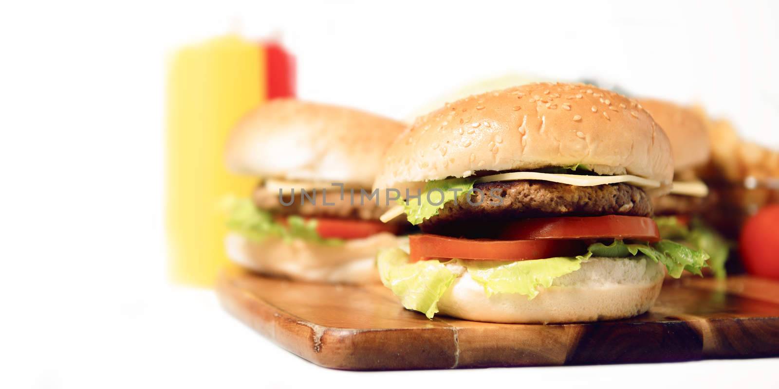 Hamburgers with cheese, potato chips and ingredients on a white background