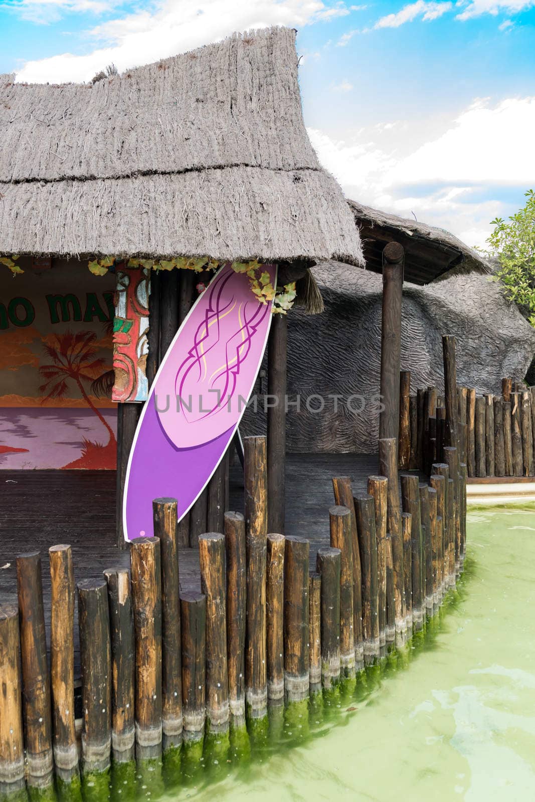 Photo shoot with Hawaiian hut and colorful surfboard.