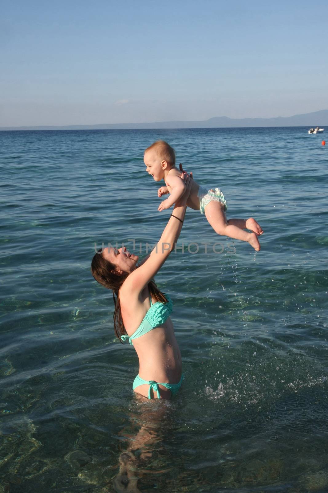 Mother playing with  her baby daughter  in the sea water