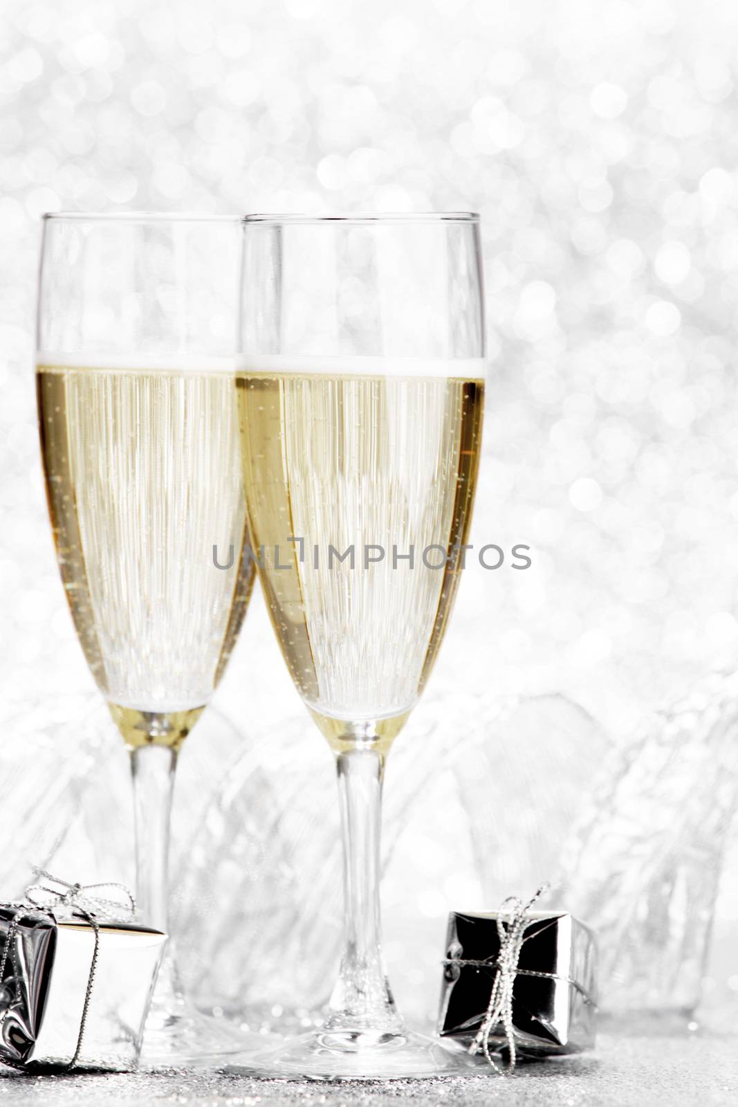 Glasses of champagne and christmas gifts on silver background