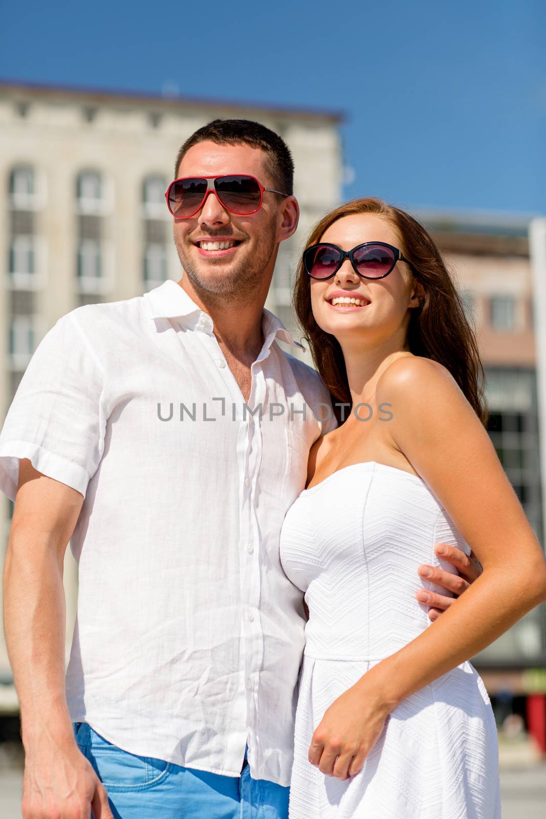 love, travel, tourism, people and friendship concept - smiling couple wearing sunglasses hugging in city