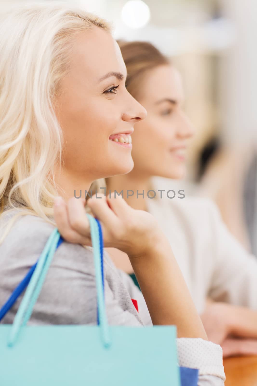 sale, consumerism and people concept - happy young women with shopping bags in mall