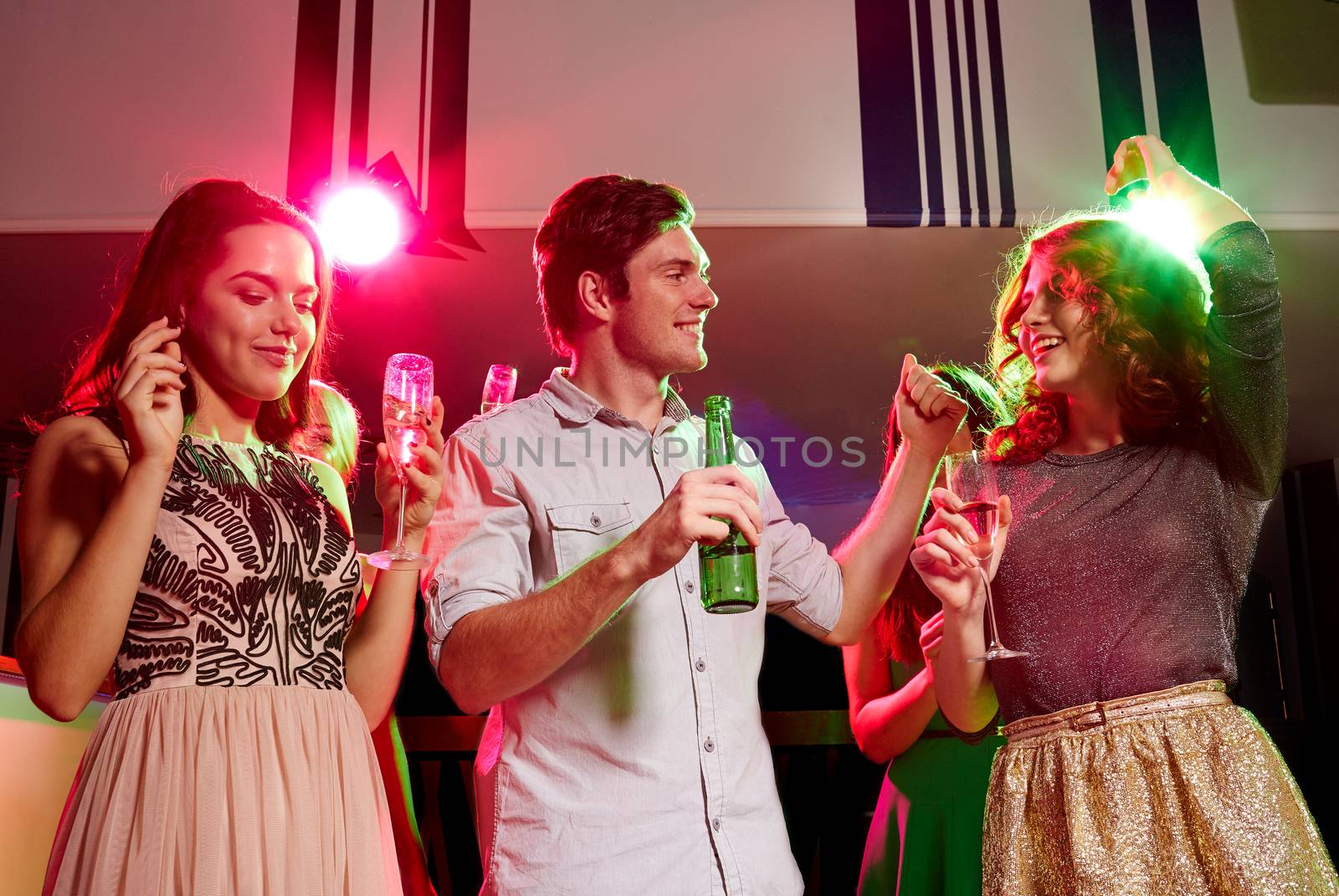 party, holidays, celebration, nightlife and people concept - smiling friends clinking glasses of champagne and beer in club