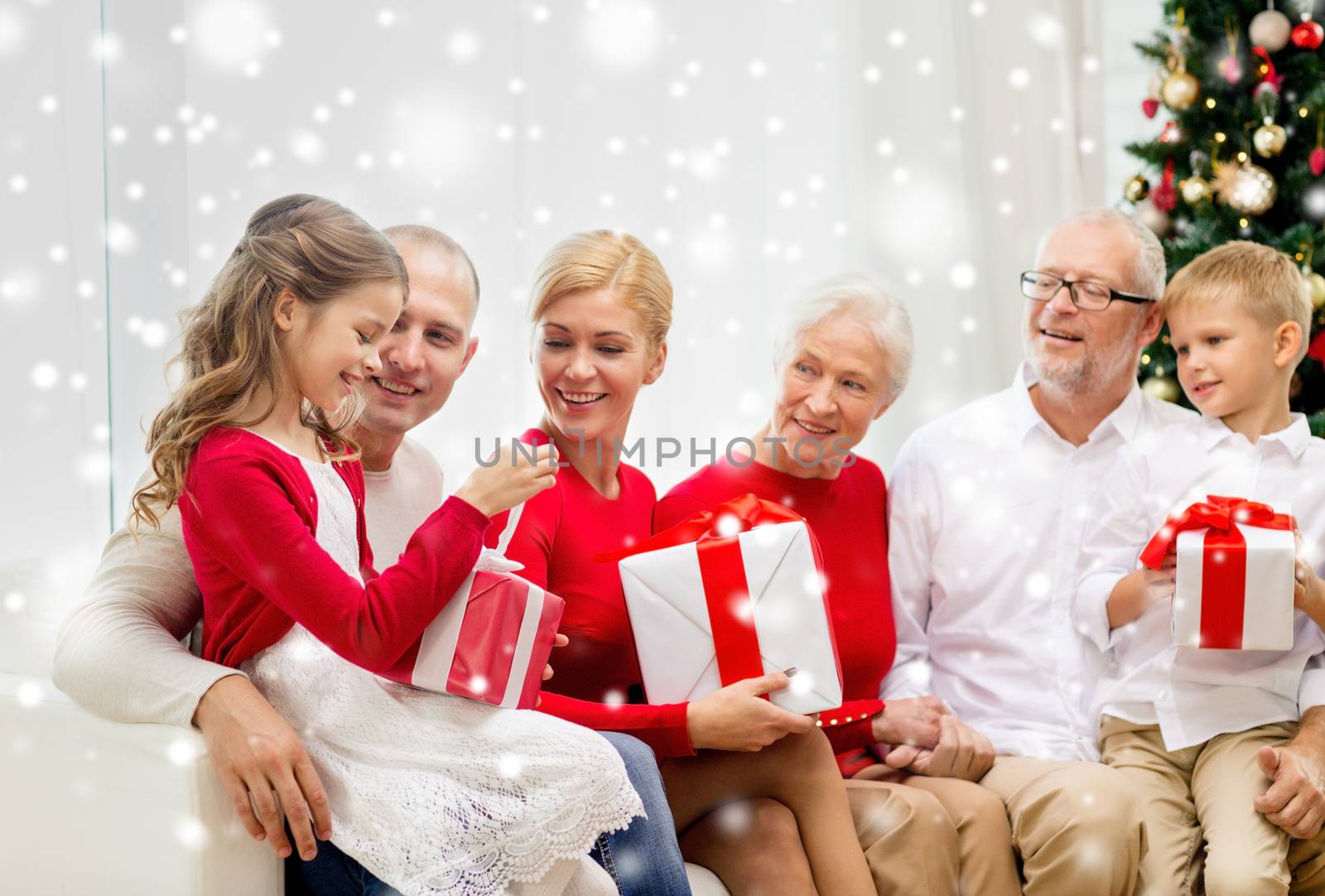 family, holidays, generation, christmas and people concept - smiling family with gift boxes sitting on couch at home