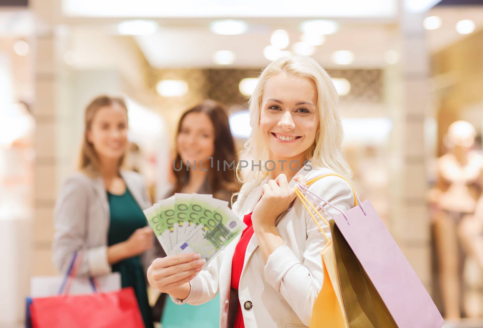 young women with shopping bags and money in mall by dolgachov