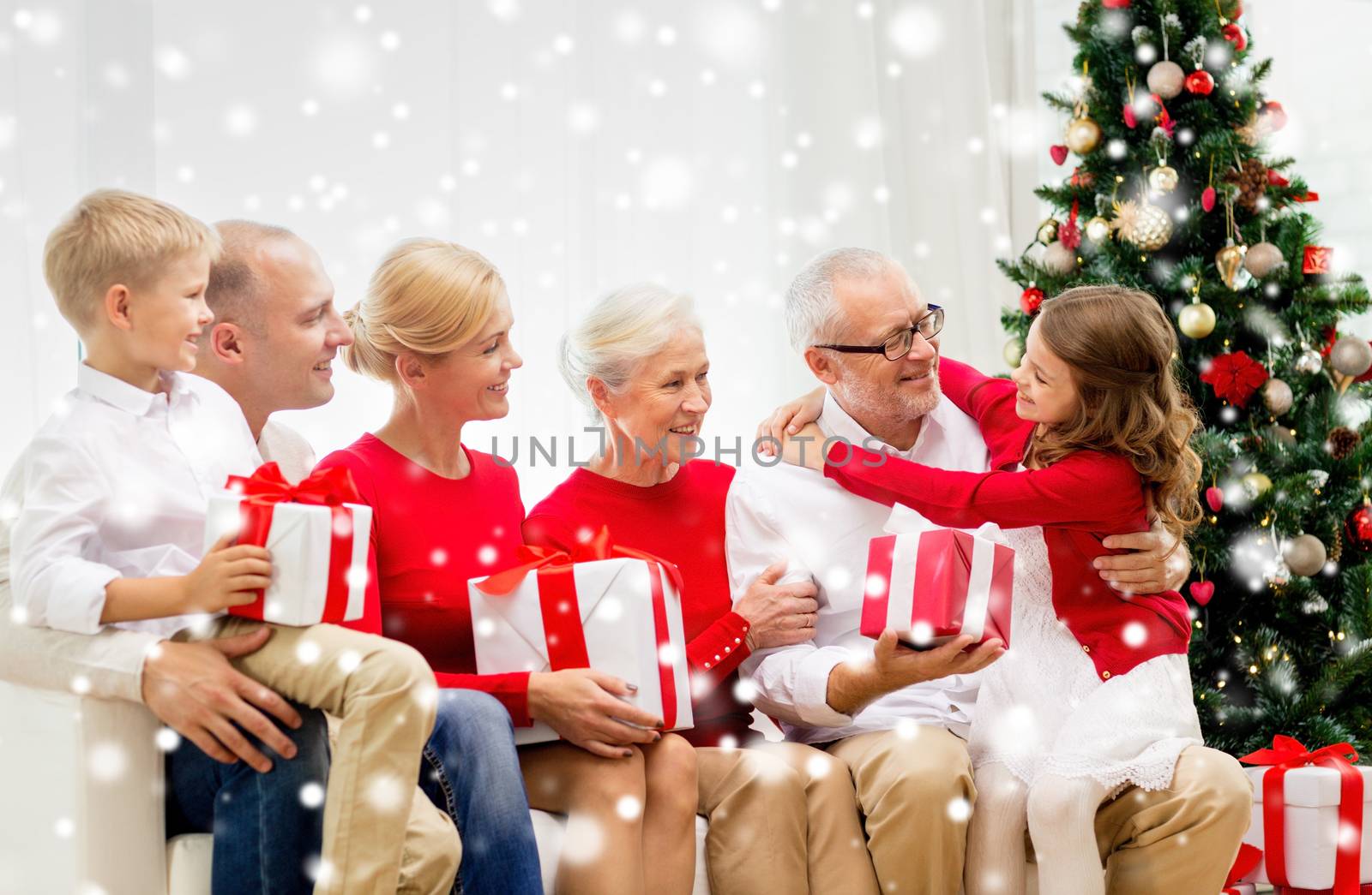 family, holidays, generation, christmas and people concept - smiling family with gift boxes sitting on couch at home