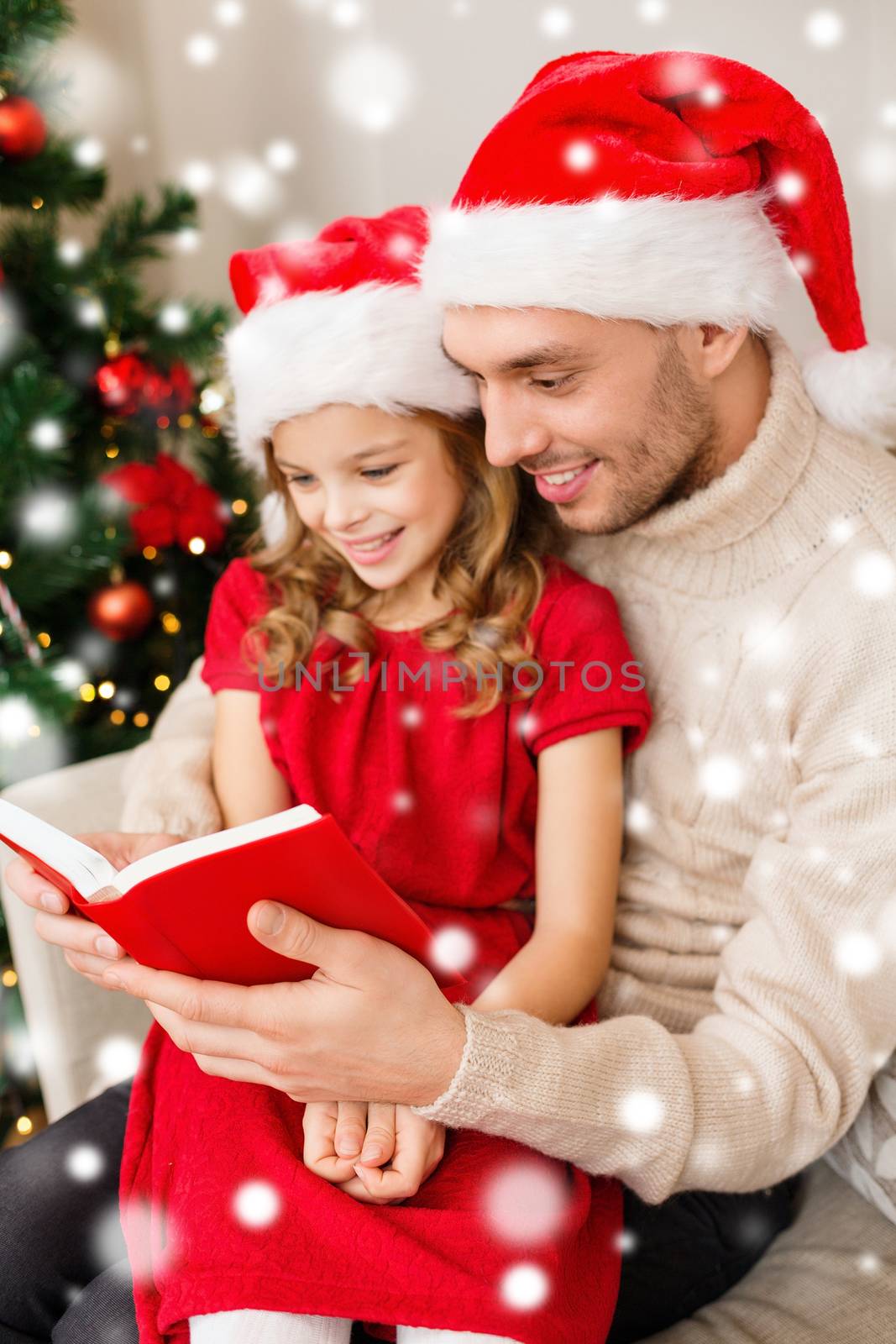family, christmas, people and holidays concept - smiling father and girl in santa hats reading book or bible at home