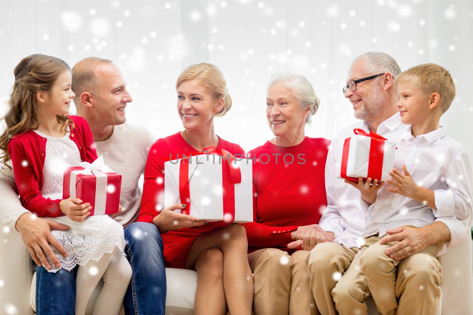 family, holidays, generation, christmas and people concept - smiling family with gift boxes sitting on couch at home