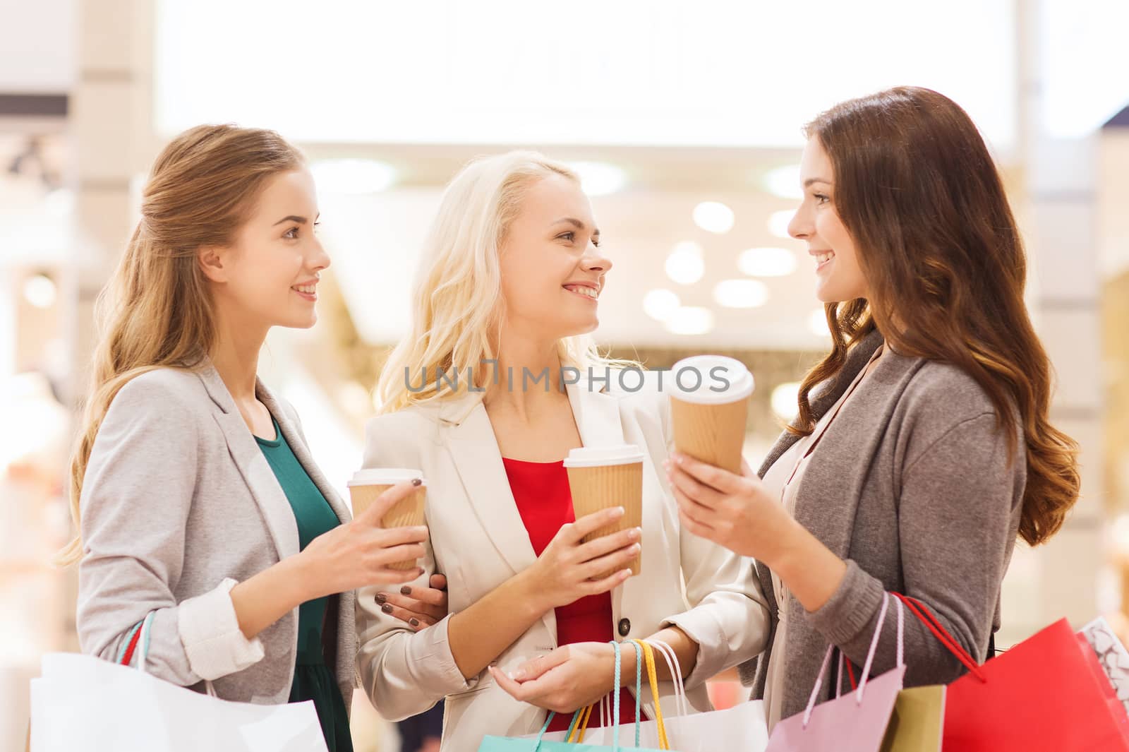 young women with shopping bags and coffee in mall by dolgachov