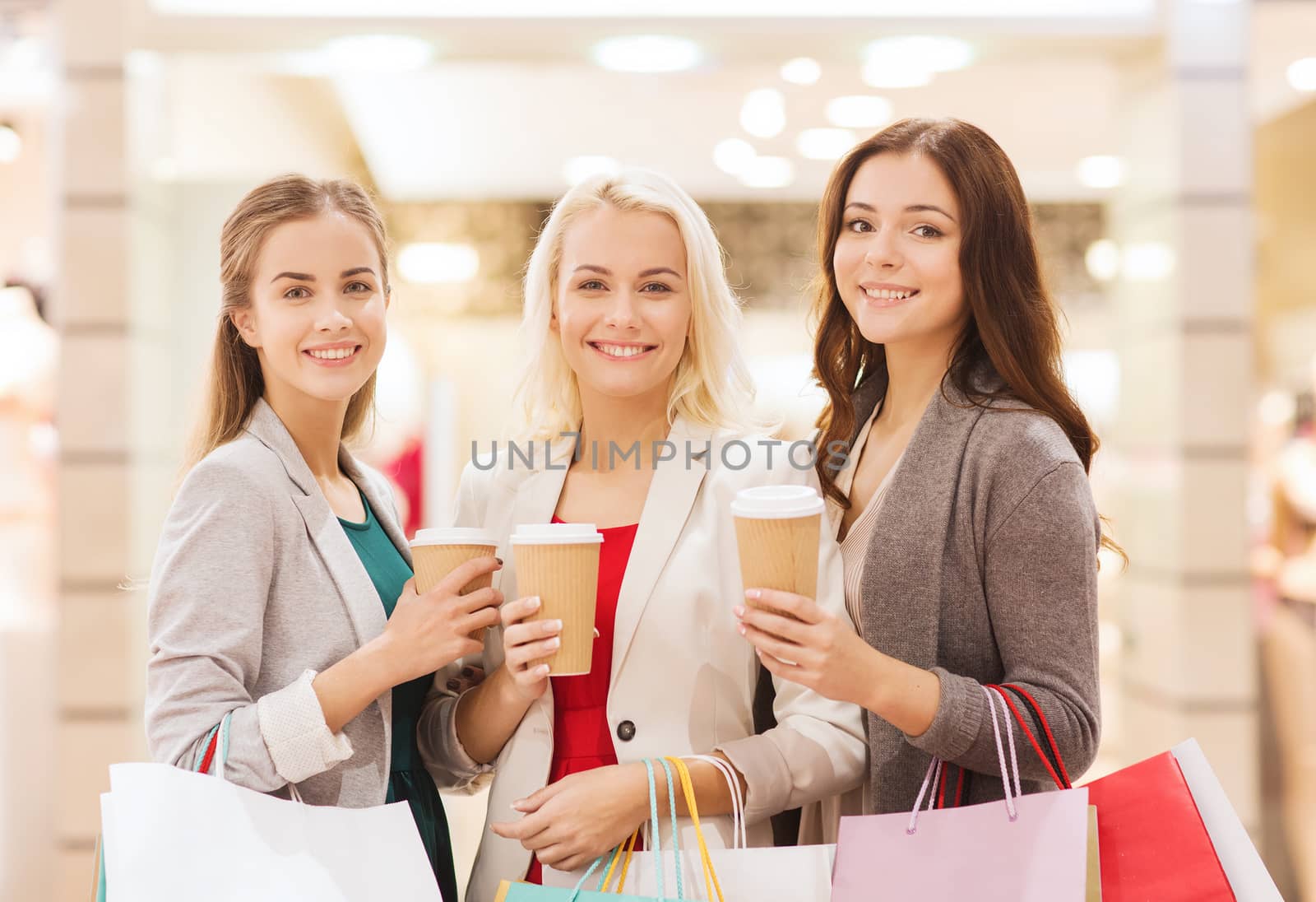 young women with shopping bags and coffee in mall by dolgachov