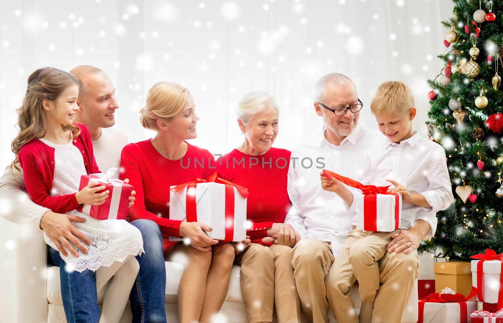 family, holidays, generation, christmas and people concept - smiling family with gift boxes sitting on couch at home