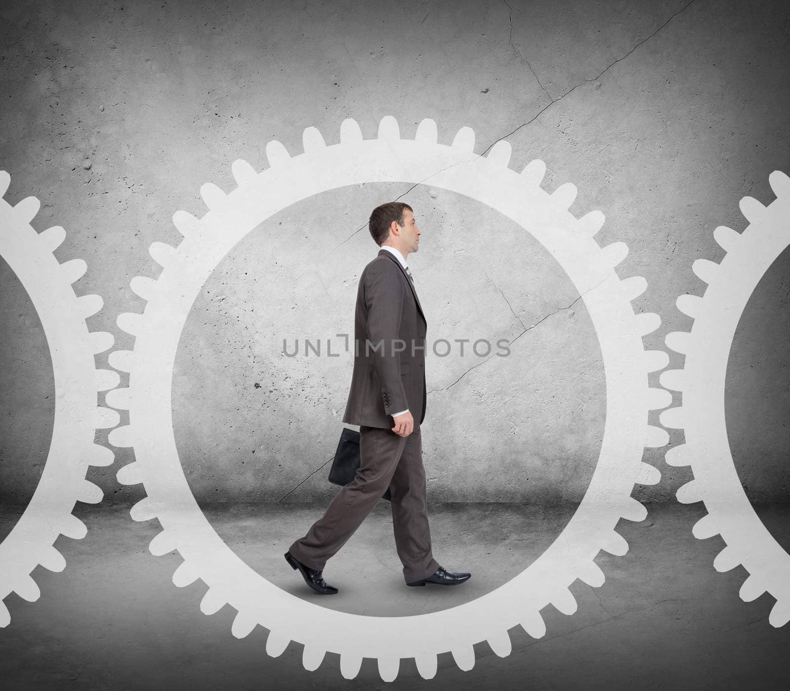 Businessman walking in cog wheel on abstract background