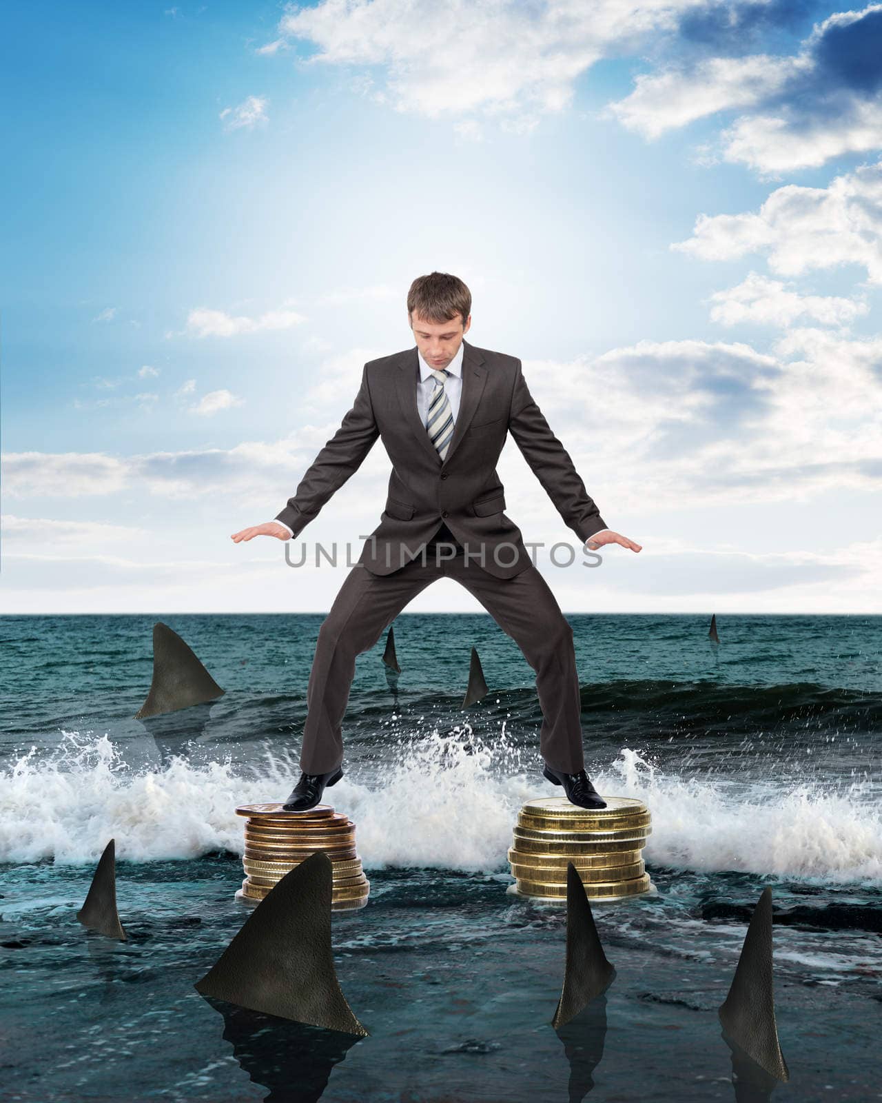 Businessman in suit standing above sharks in water