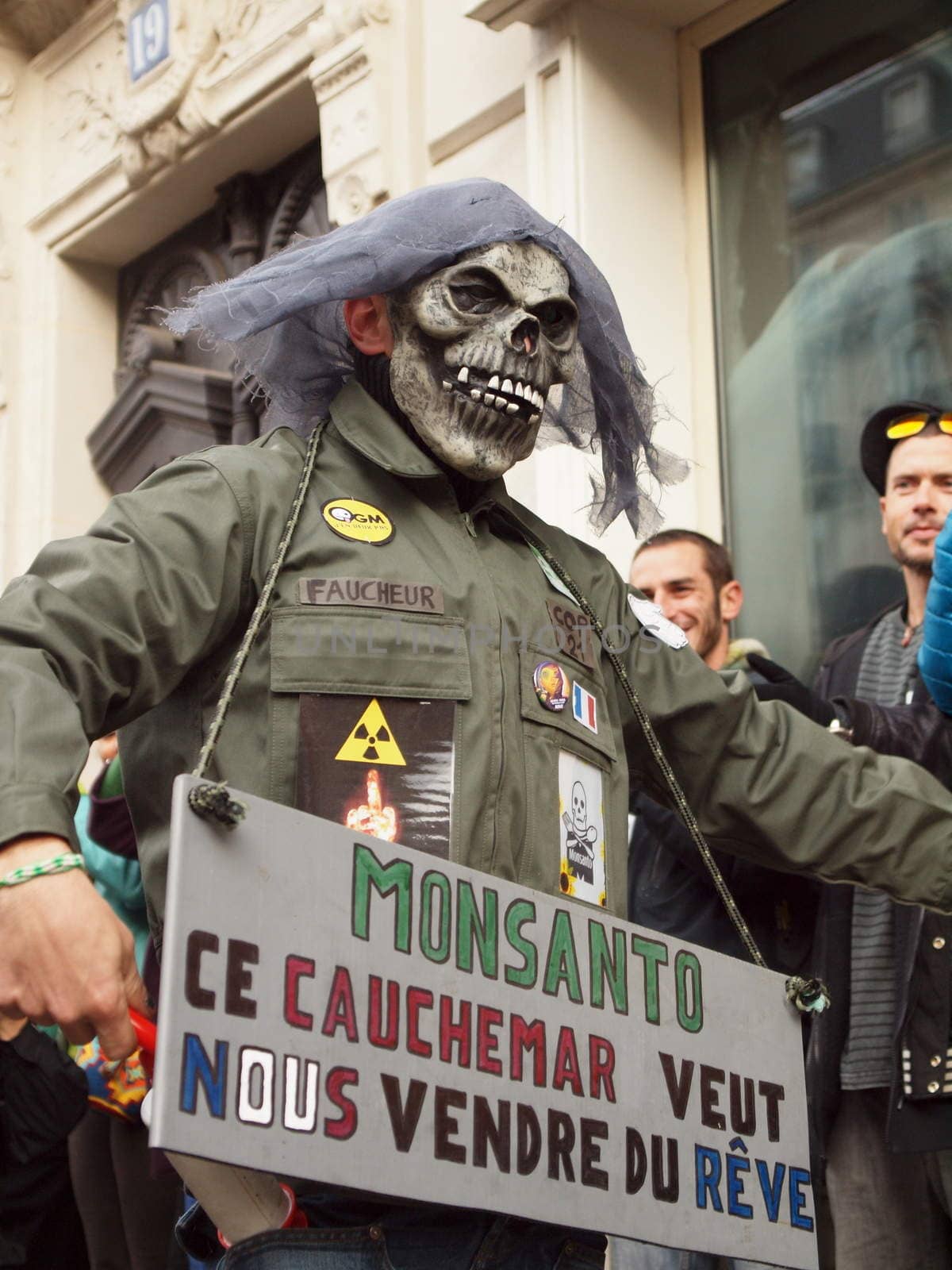 FRANCE, Paris : A man wearing a skull mask holds a sign reading Monsanto, this nightmare wants to sell us dreams as he participate in a human chain on the streets of Paris on November 29, 2015.  Despite the ban, hundreds of people gathered to promote climate protection as COP 21 negotiations start. 