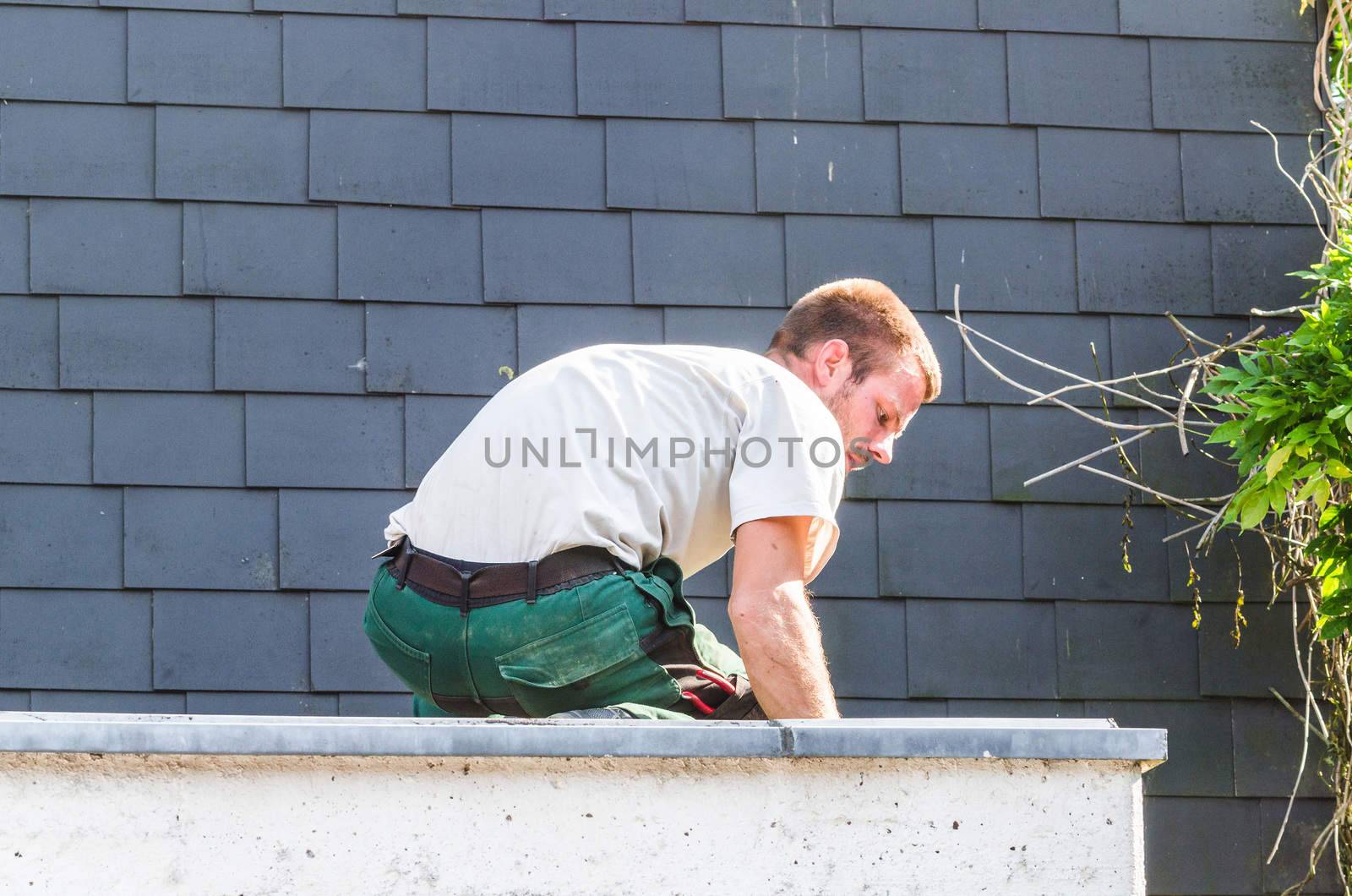 Construction worker on the roof of a garage to fix the damage of a tornado.