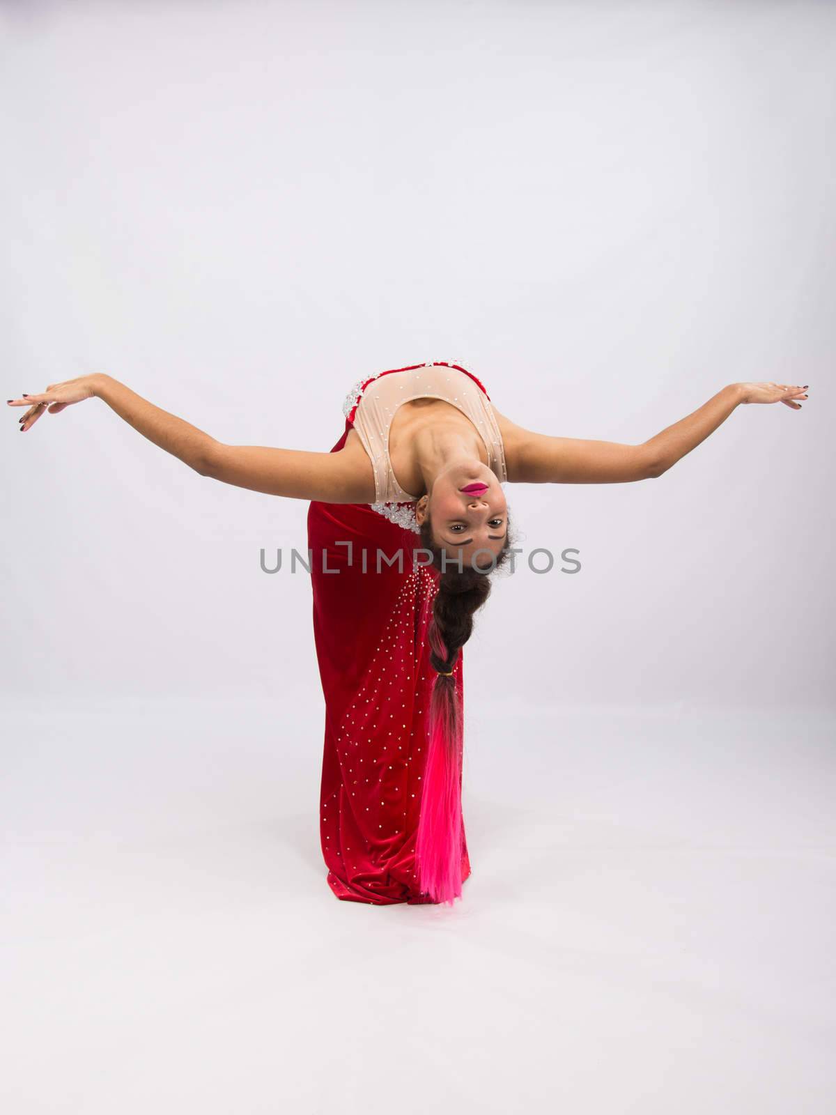 Mulatto girl dancer performs a dance elements, isolated on a light background