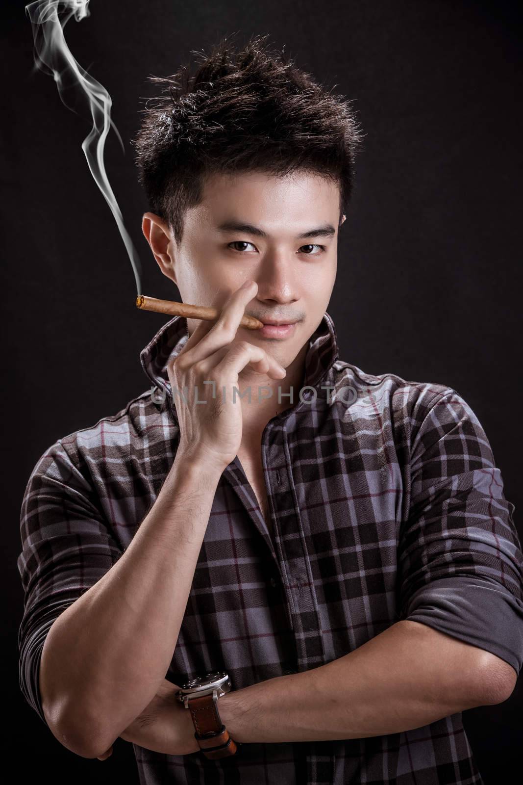 Portrait of Asian young man on black background - handsome young man hold cigar