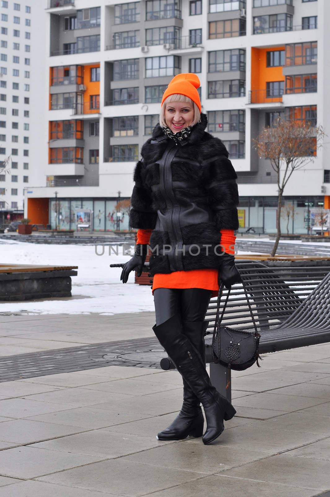 The woman in a fur coat costs against new buildings.