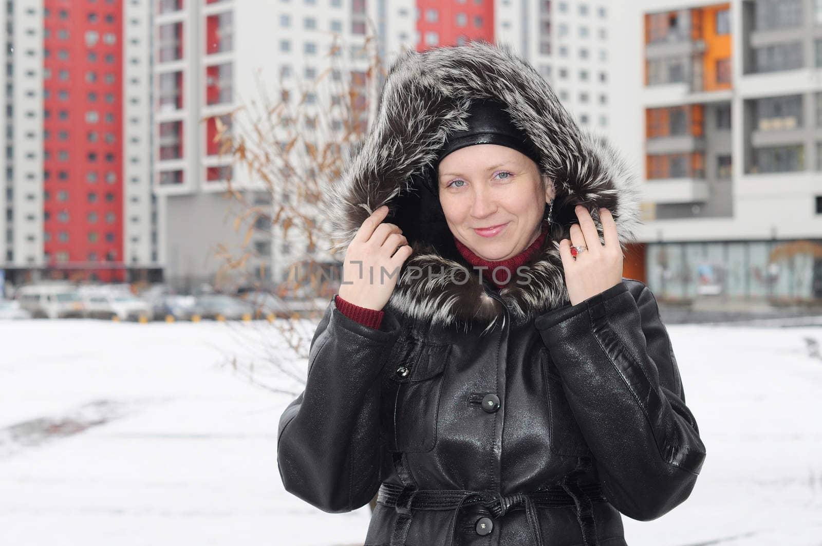 The woman in a sheepskin coat costs against new buildings.