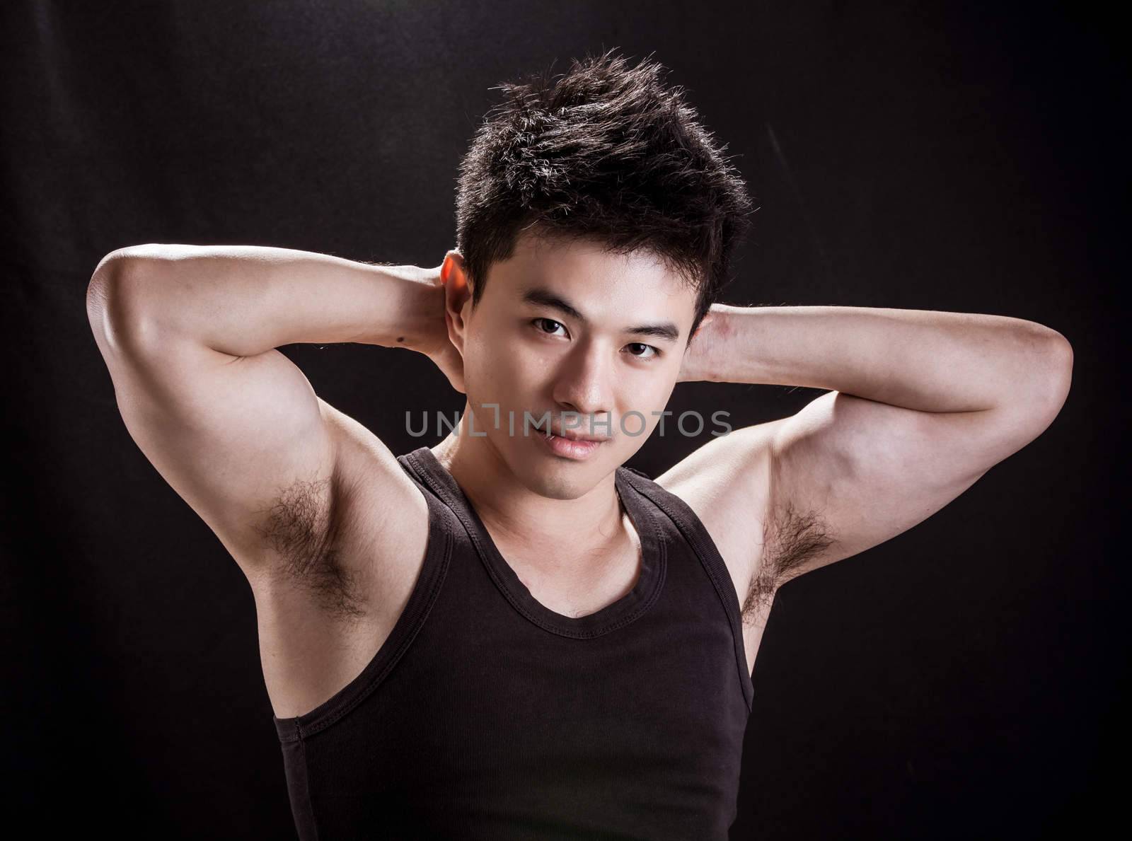 Portrait of Asian young man on black background - Show muscle and strengh