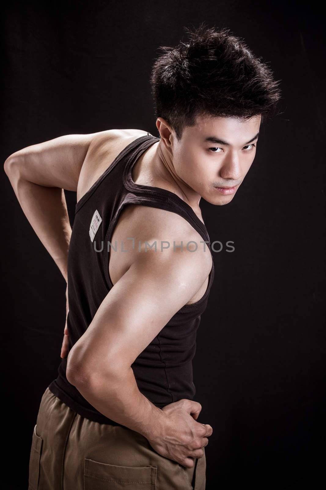 Portrait of Asian young man on black background - Show muscle and strengh