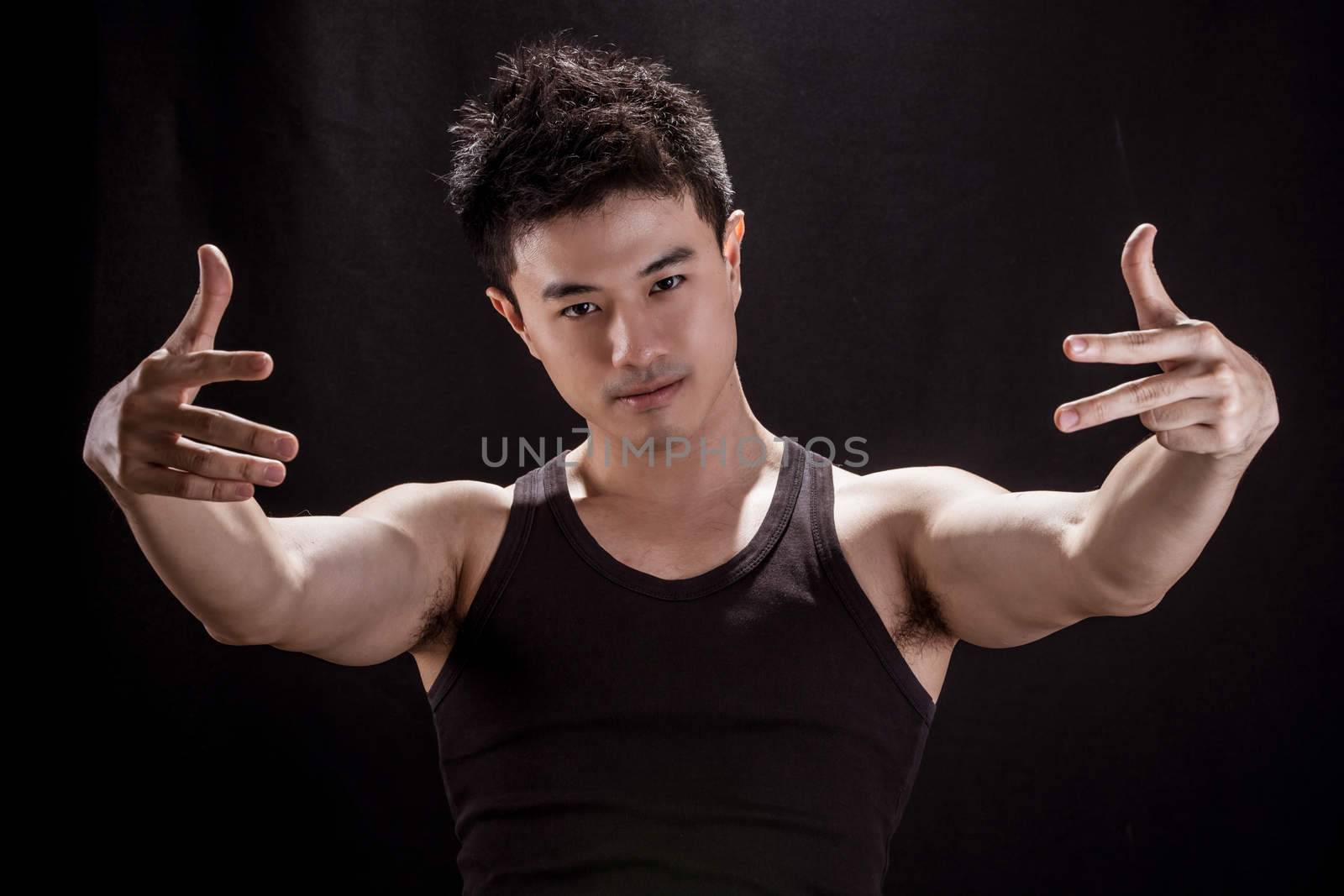 Portrait of Asian young man on black background - Show muscle and strengh